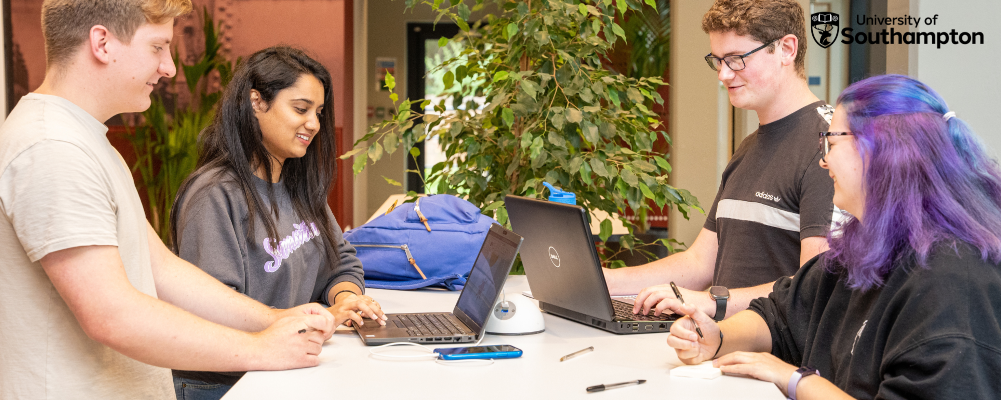 a group of people sitting at a table using a laptop computer