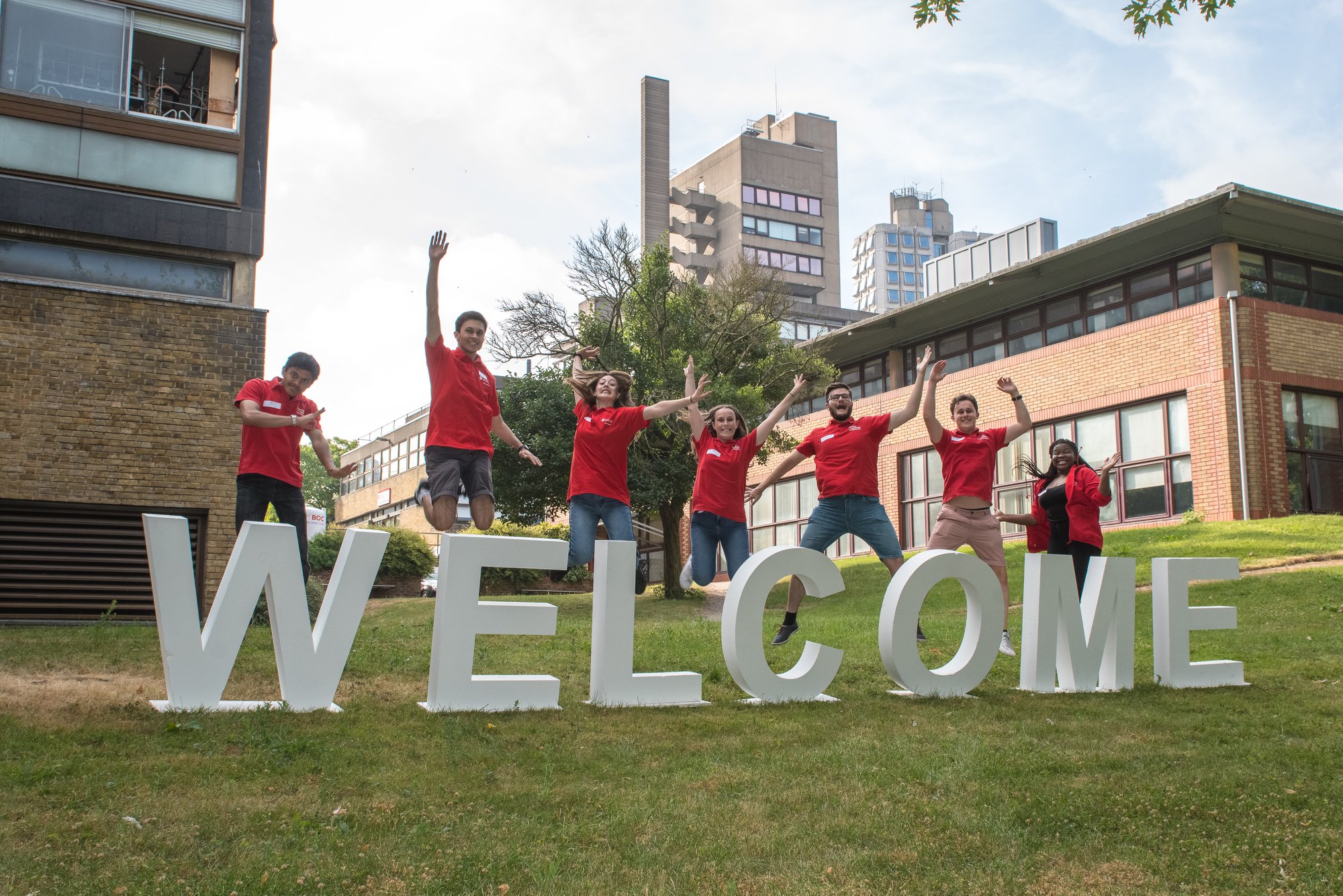 a group of student ambassadors jumping above a sign saying welcome