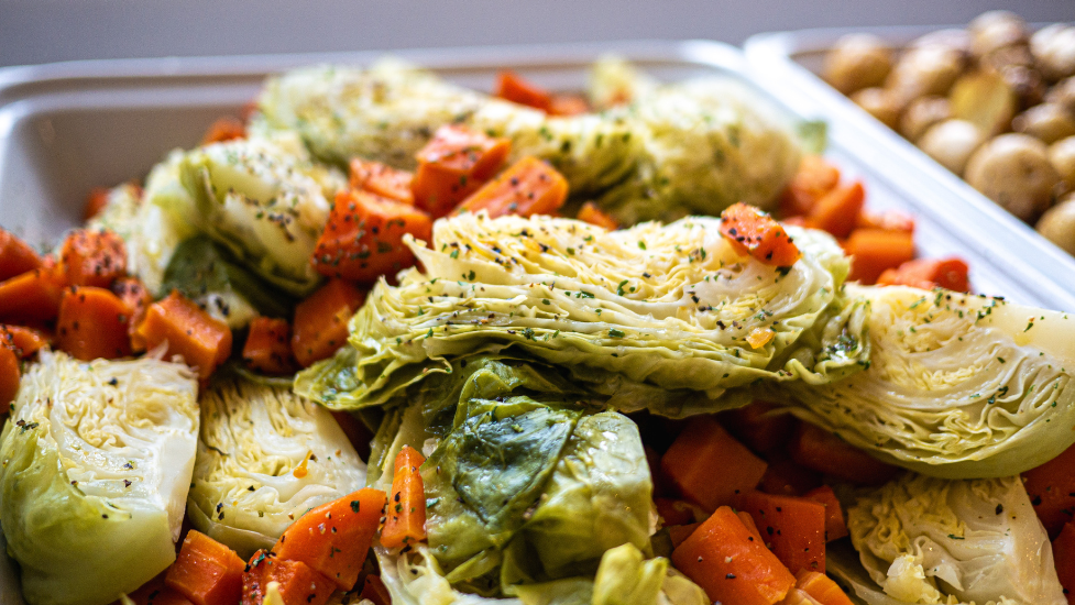 A close up shot of cabbage and carrots with seasonings on in a white tray.