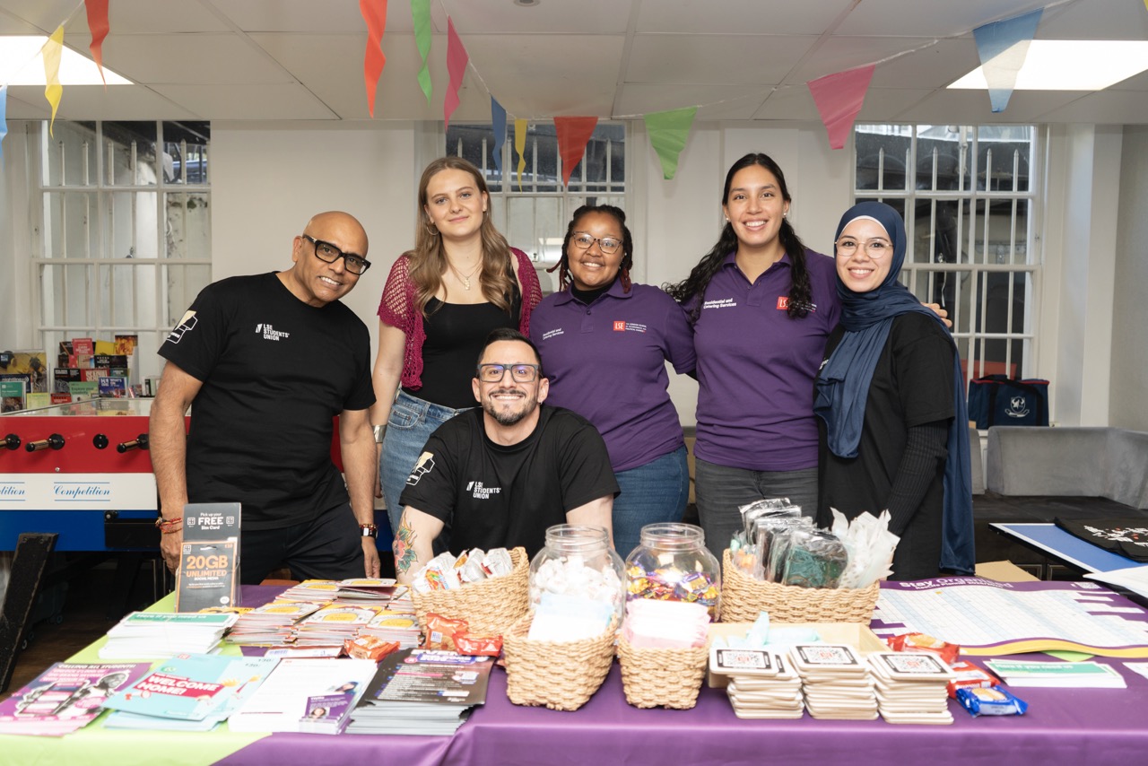 a group of people sitting at a table with a cake