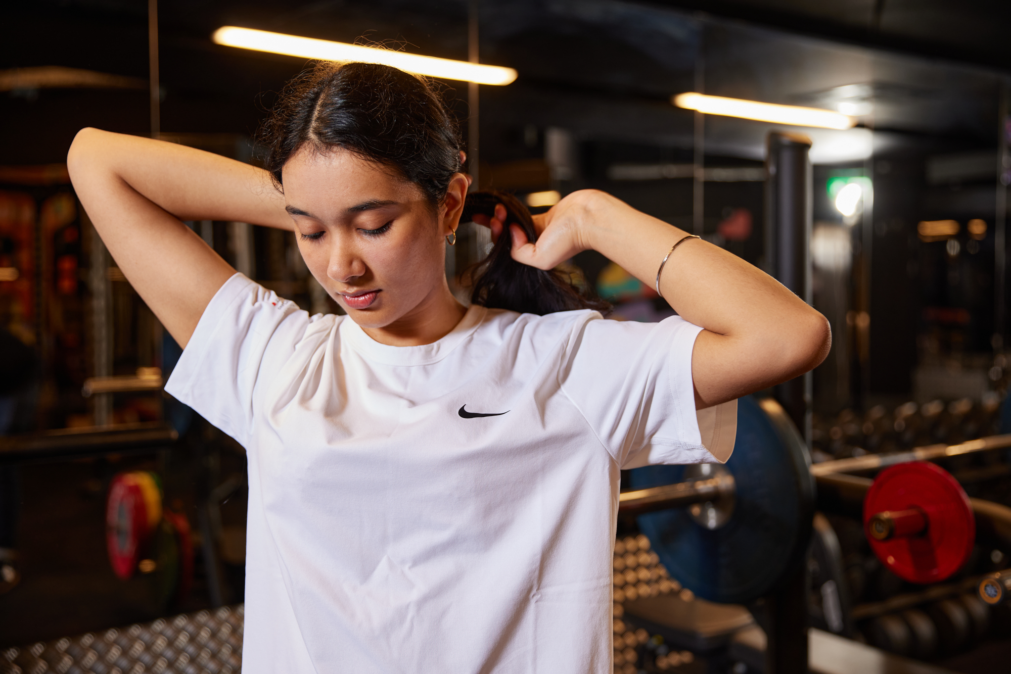 a girl tying her hair up in a gym