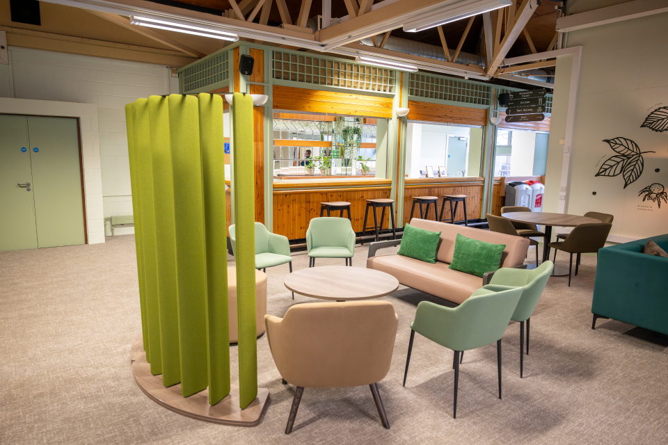Soft chairs around a table, partitioned with an acoustic screen, in Woodland Lounge