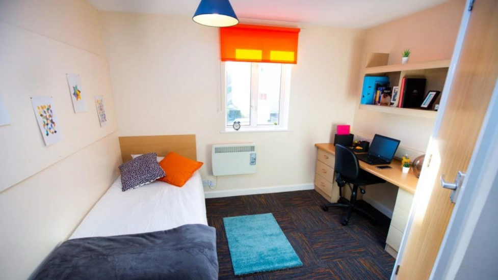 a bedroom with a bed and desk in a room